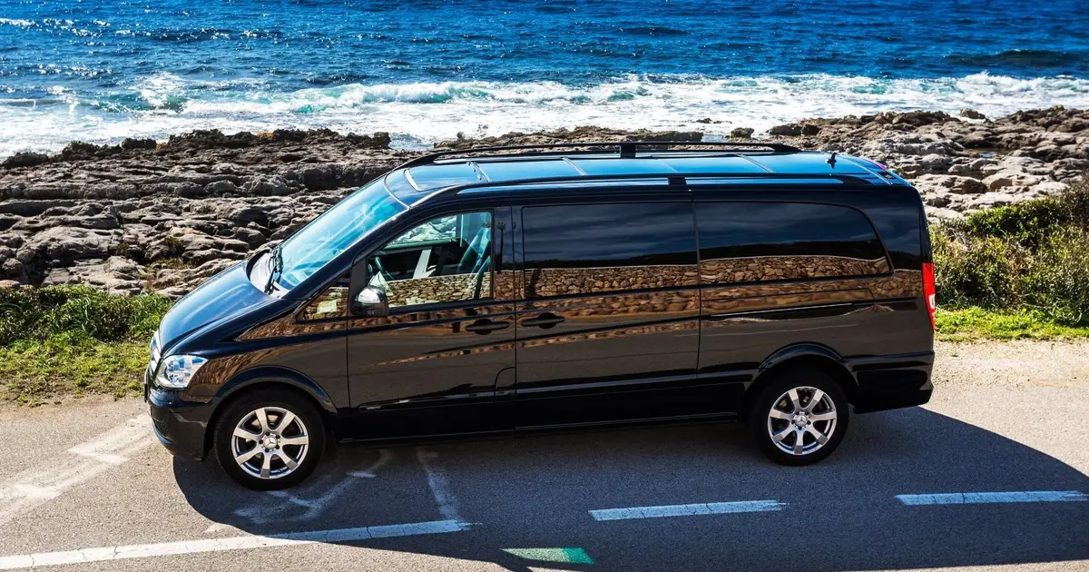 Ein 10-Sitzer-Minibus Mercedes Sprinter, geparkt in der Nähe des Meeres in Mahón